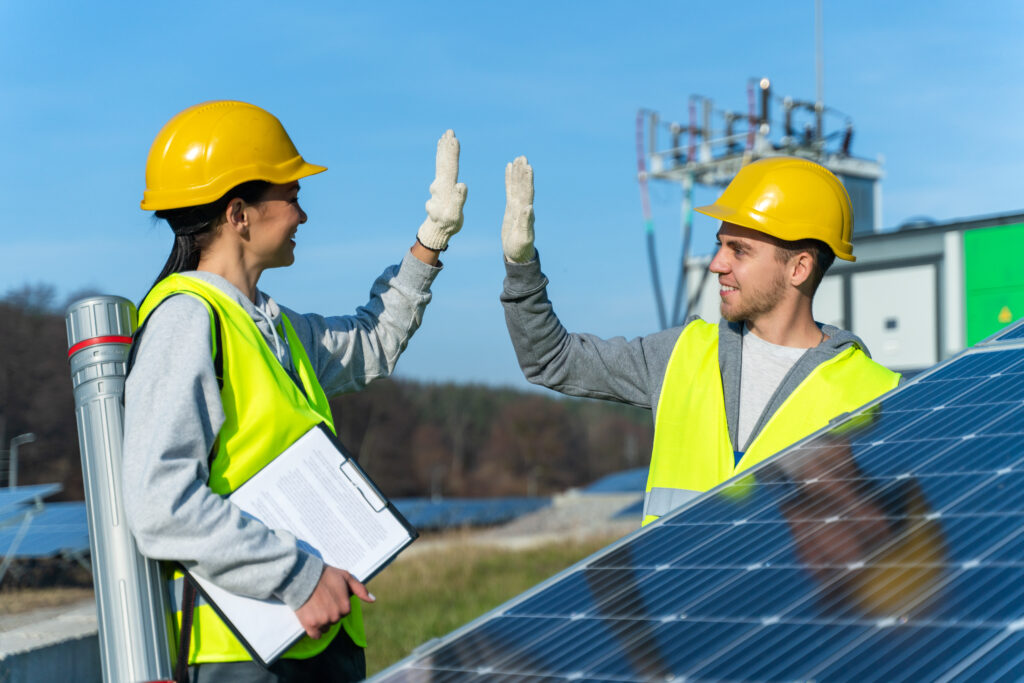 two experienced solar panel workers hardhat vests giving five each other feeling happy while agreed about something scaled